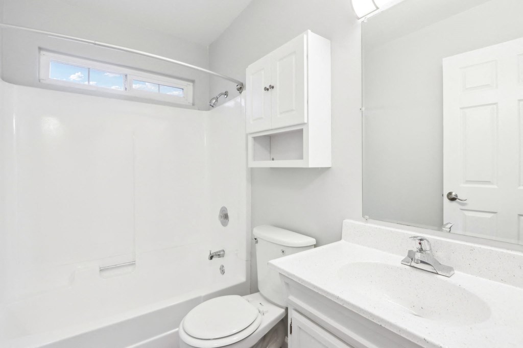 A white bathroom with a toilet, sink, and medicine cabinet.