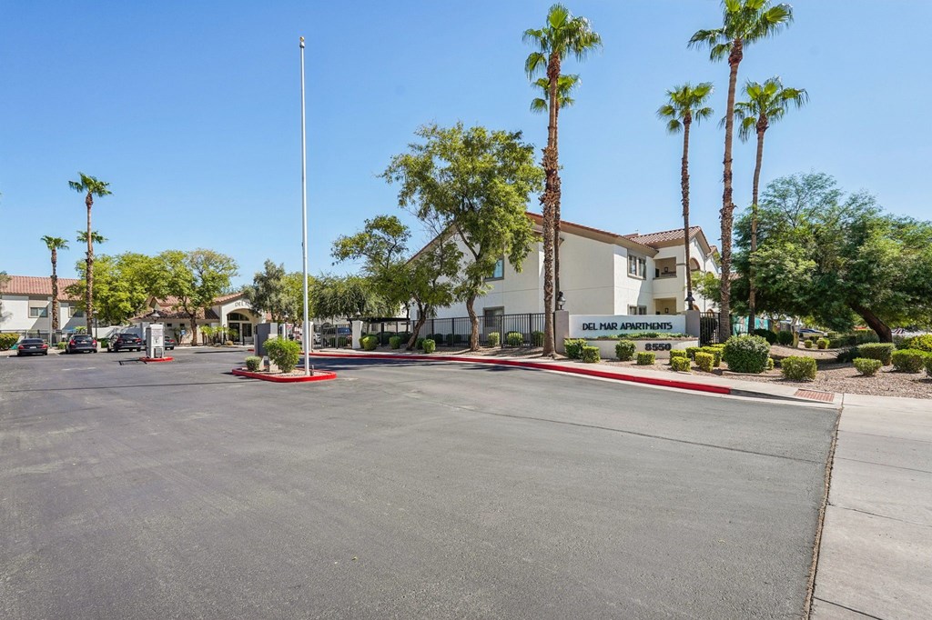 A parking lot with a building and palm trees in the background.