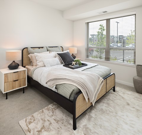 A bedroom with a large bed and a window with blinds.