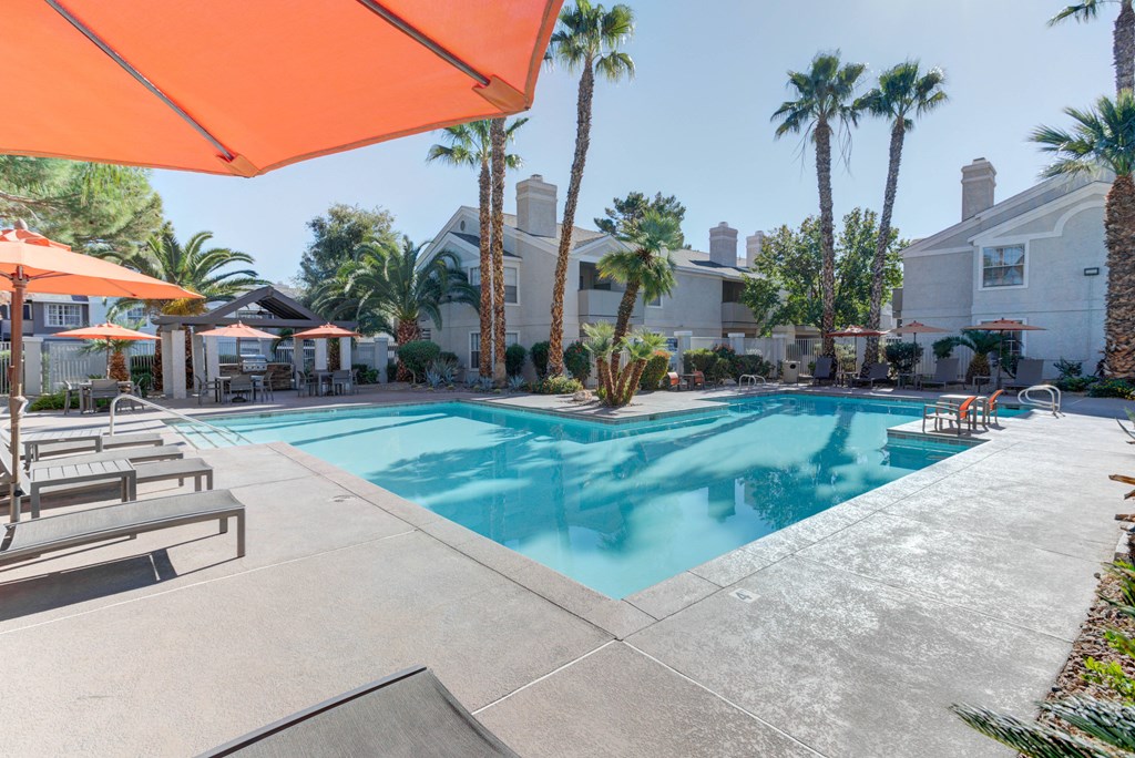 a swimming pool with palm trees and a building in the background