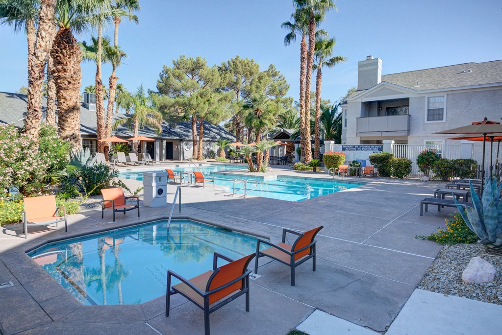 a large swimming pool with chairs and palm trees