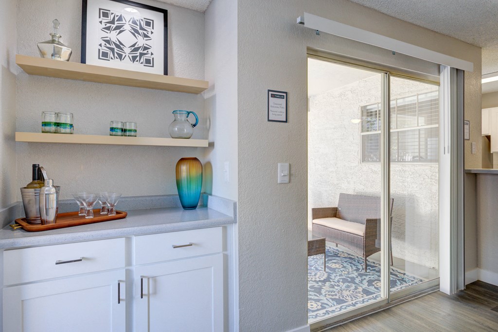 a kitchen with white cabinets and a sliding glass door to a patio