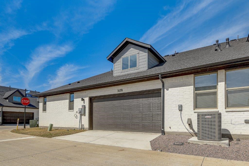 Two Bedroom Single Family Homes for Rent in Arlington TX - Legacy Park at Viridian - Back of Rental Home with a Black Garage Door and a Drive Way