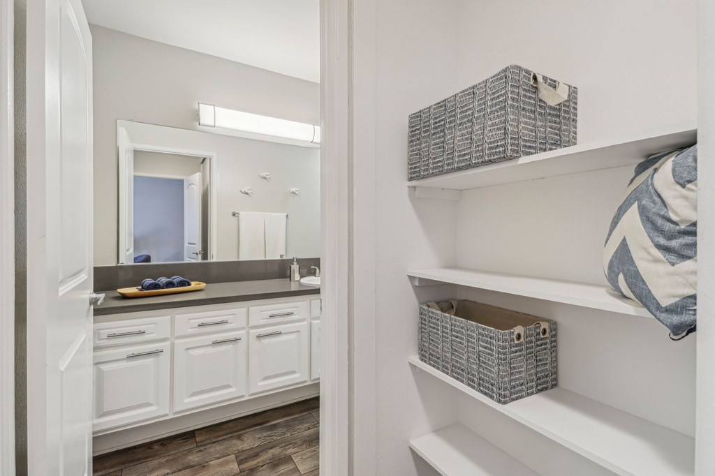 A bathroom with white cabinets and a mirror.