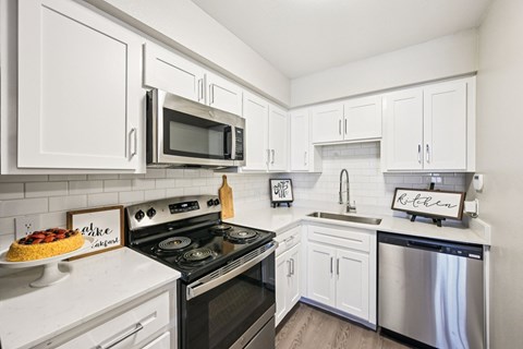 A kitchen with white cabinets and appliances.