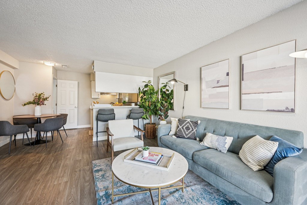 A living room with a grey couch, a coffee table, and a dining table with chairs.