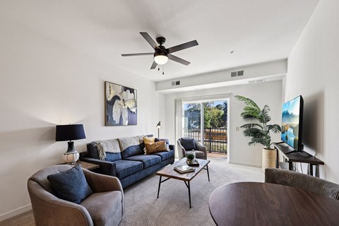 A living room with a blue couch and a ceiling fan.