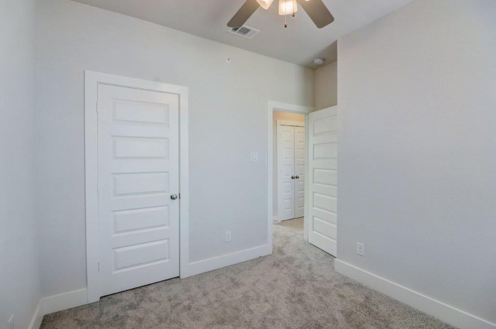 an empty bedroom with white doors and a ceiling fan