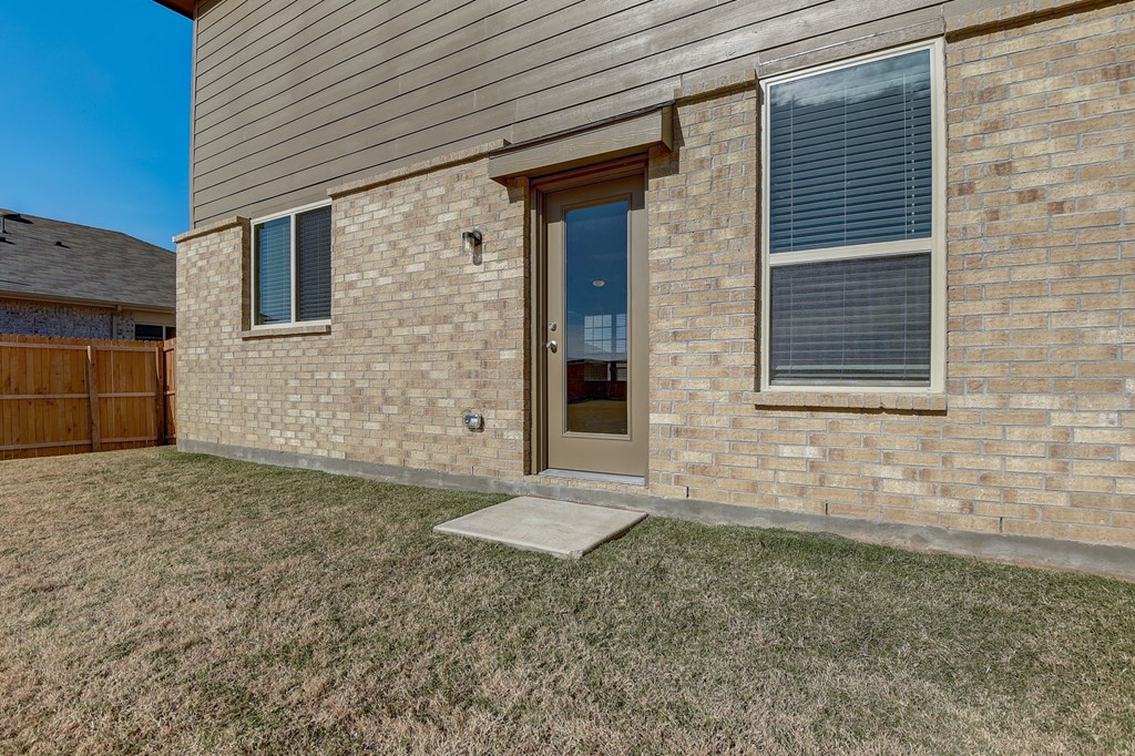 the front door of a brick house with a patio and grass