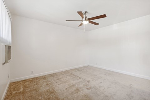 A room with a ceiling fan and carpeted floor.