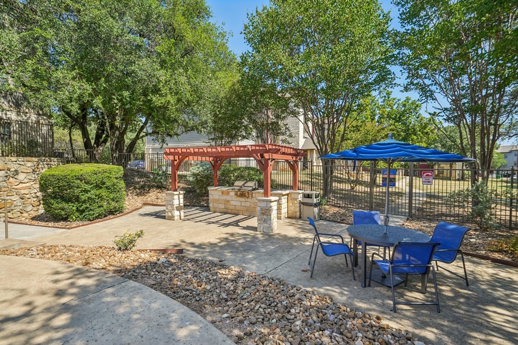 A backyard with a table and chairs and a red archway.
