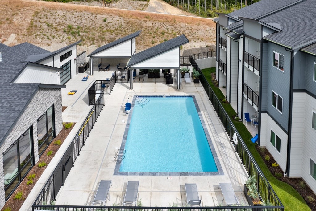 Apartments for Rent in Belfair, WA - Belfair View - Aerial View of  Pool with Lounge Chairs and Patio Furniture.
