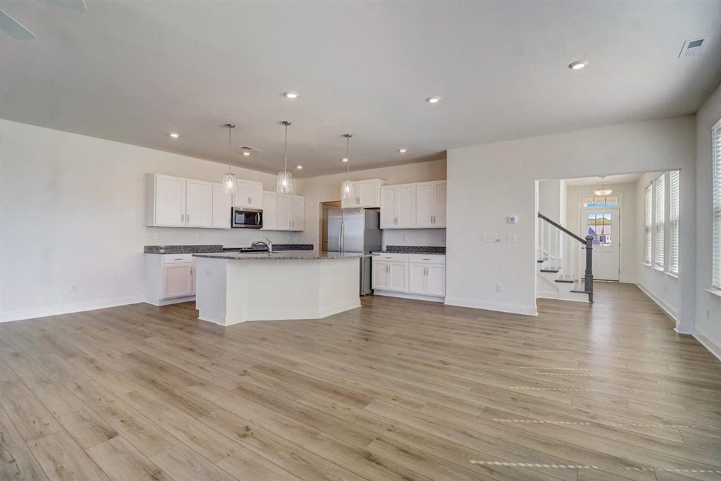 an open kitchen and living room with a staircase in the background