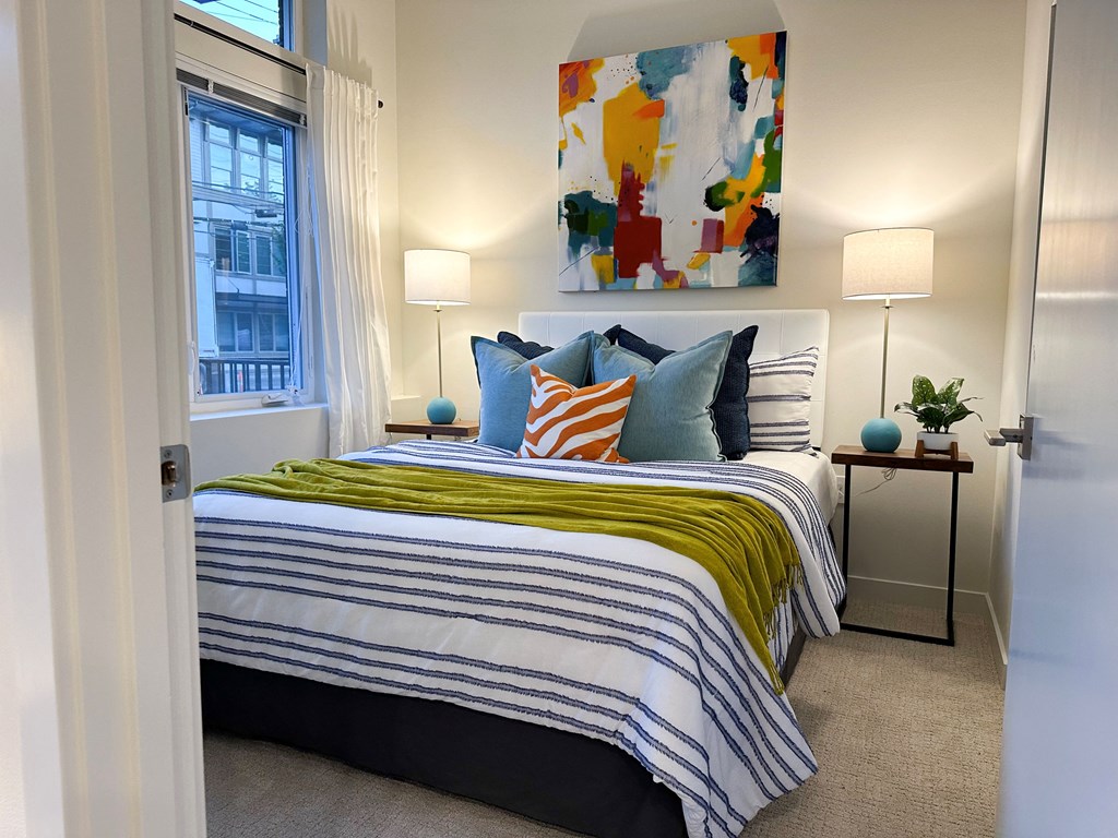 1-Bedroom Apartments in Bothell, WA - Morado Bothell - Bedroom with Carpeted Flooring, Bed, Nightstands, Nightstands with Lamps, Wall Art, and Large Window.