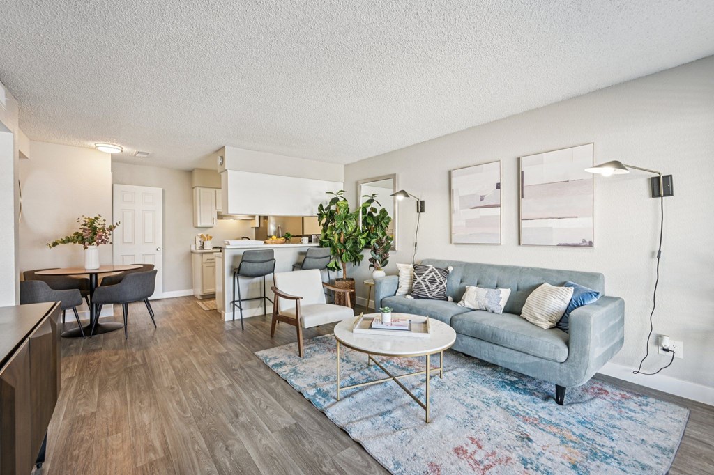 A living room with a grey couch, a coffee table, and a dining table with chairs.