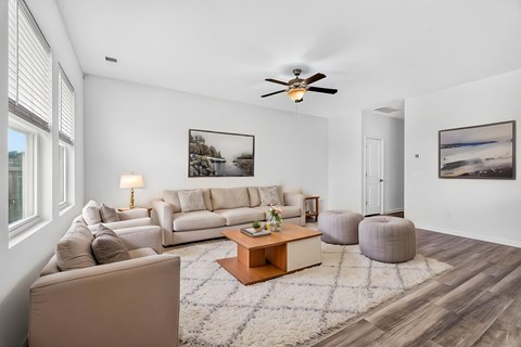 A living room with a white couch, a coffee table, and a ceiling fan.
