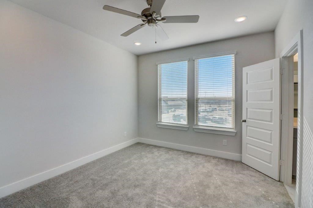 an empty room with a ceiling fan and two windows