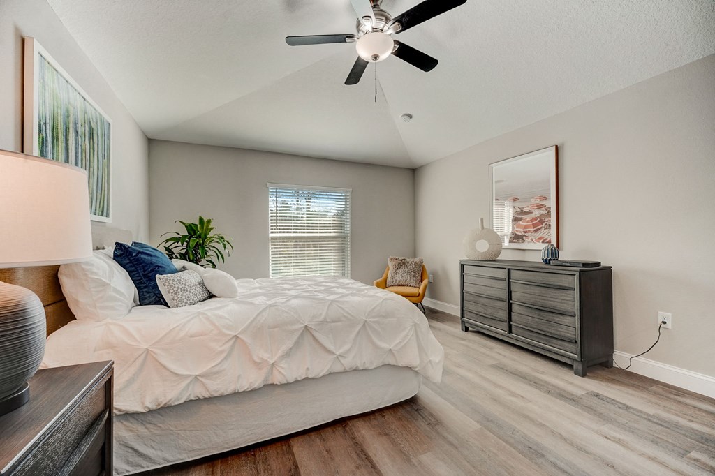 Master bedroom with a large bed and ceiling fan at The Groves at Lake Ella in Lady Lake, Florida, a pet-friendly rental community.