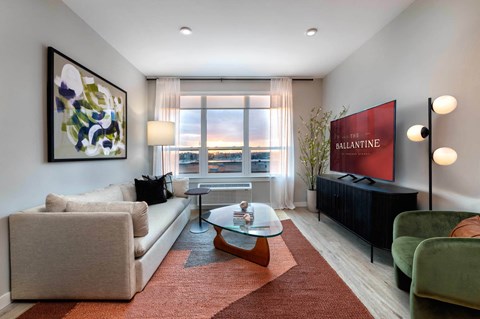 A living room with a large window, a sofa, a coffee table, and a painting on the wall.
