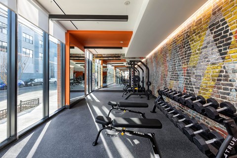 A gym with a brick wall and a row of exercise equipment.