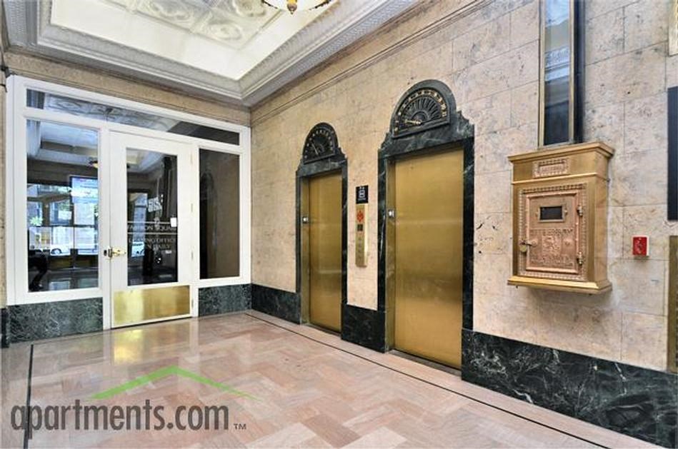a lobby with two elevators and a grandfather clock