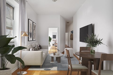 A living room with a white couch, a wooden table, and a television on the wall.