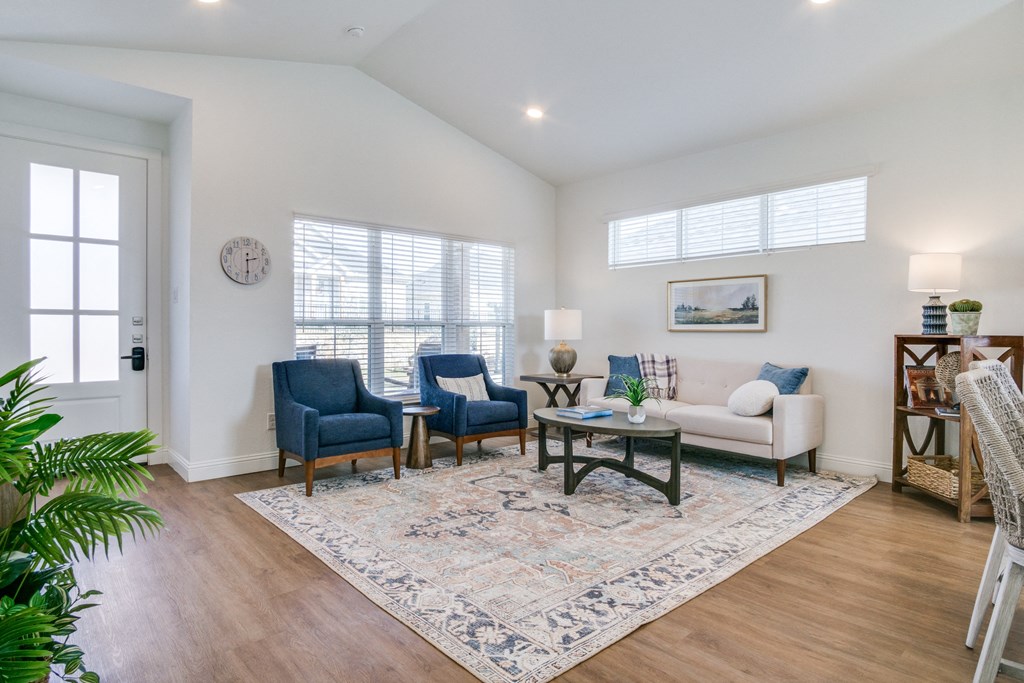 A living room with a sofa, two chairs, a table, and a rug.