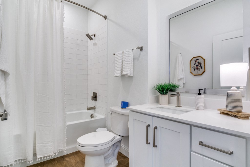 A white bathroom with a toilet, sink, and shower.