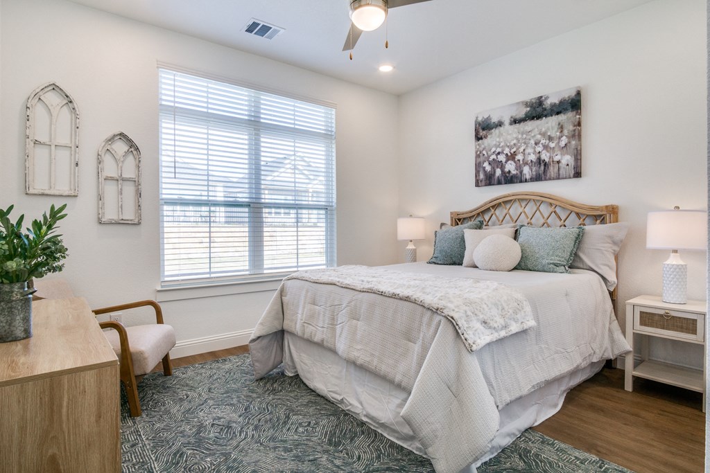 A bedroom with a large bed and a window with blinds.