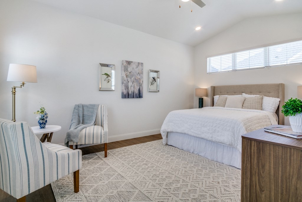 A bedroom with a bed, chair, and lamp.