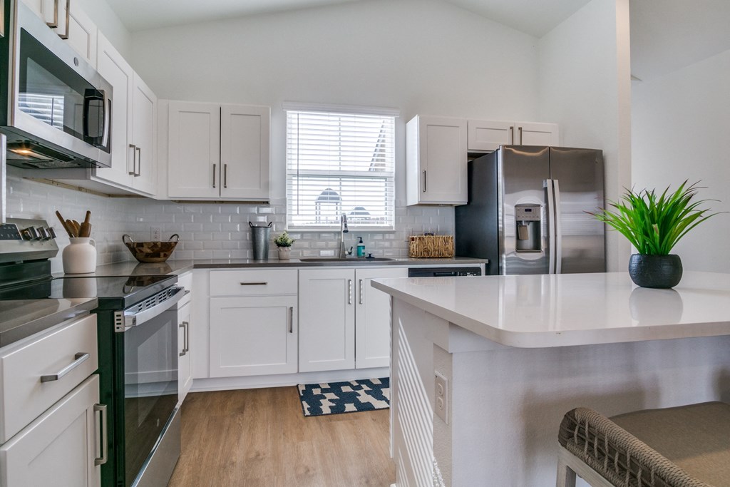 A kitchen with white cabinets and a black countertop.