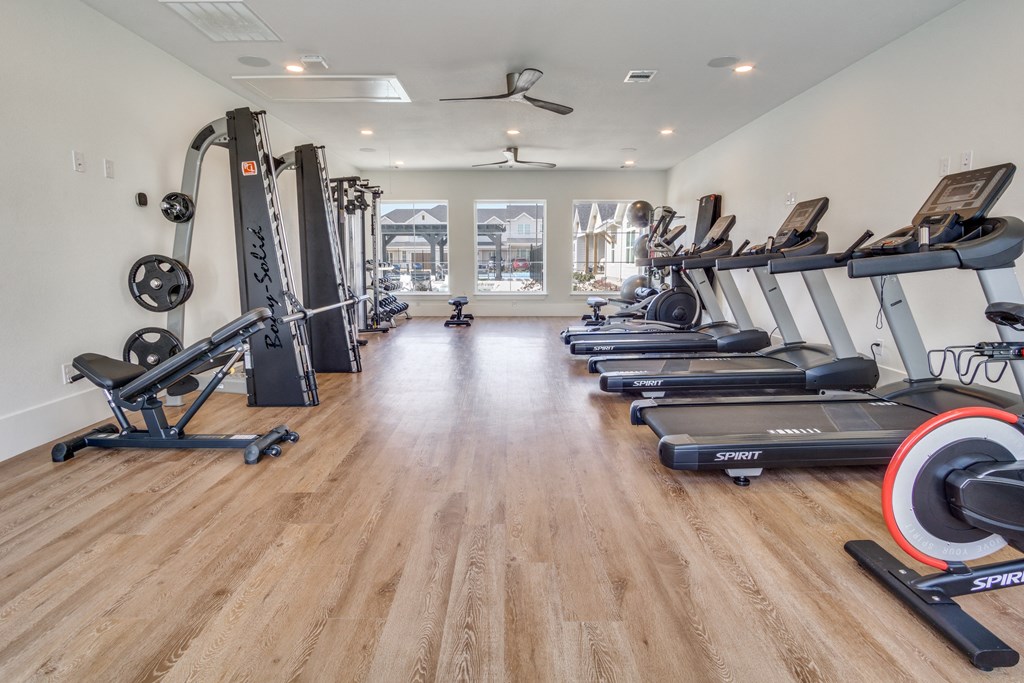 A spacious gym with a variety of equipment including treadmills, elliptical machines, and weight racks.
