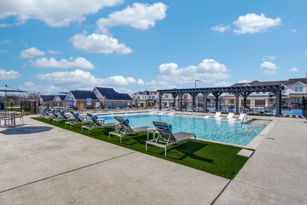 A pool area with chairs and a bridge in the background.
