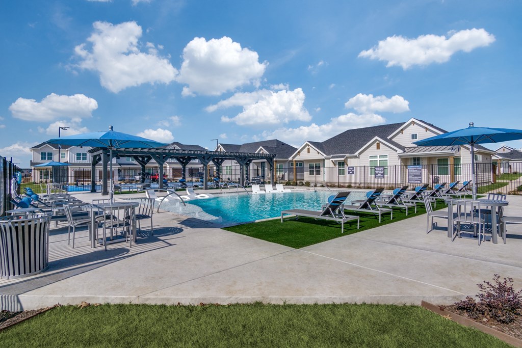 A large outdoor swimming pool surrounded by lounge chairs and umbrellas.