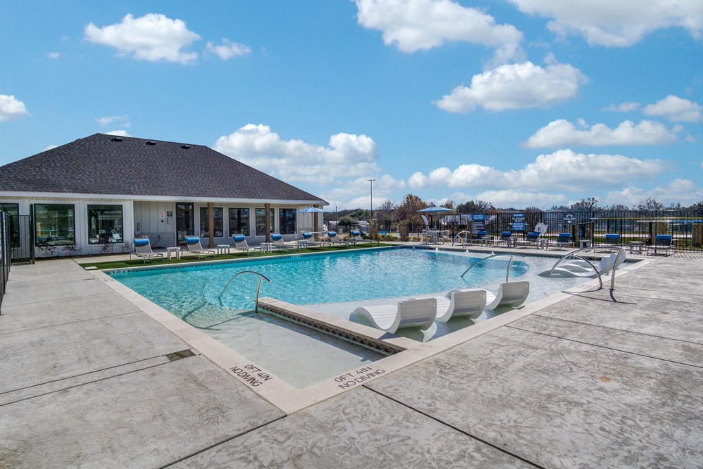 A large outdoor swimming pool with a building in the background.