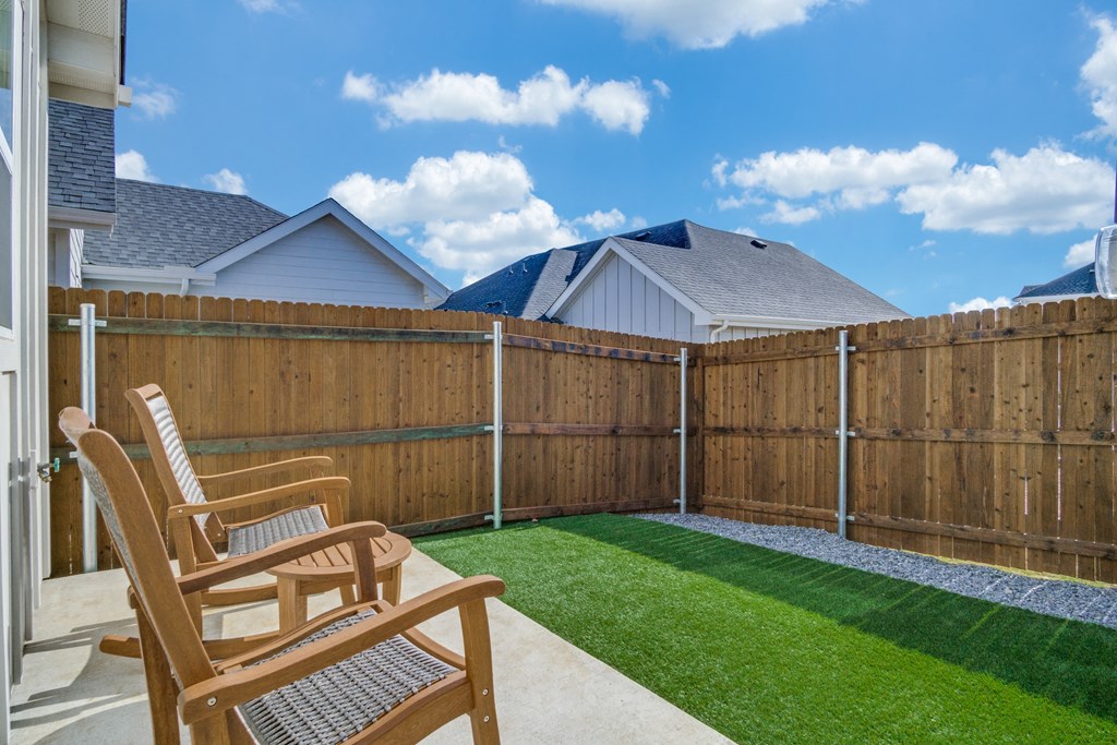 A backyard with a wooden fence and two chairs.