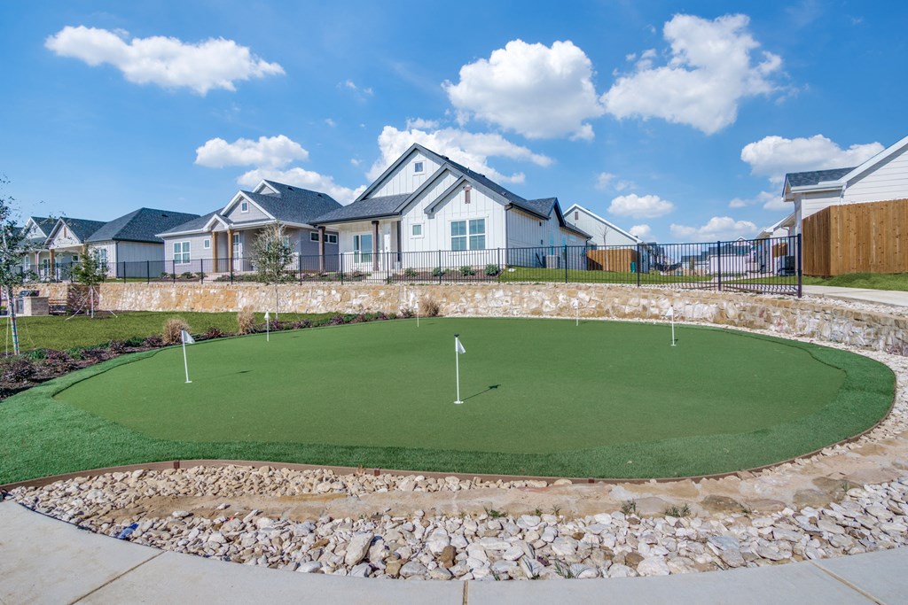 A small putting green in front of a row of houses.