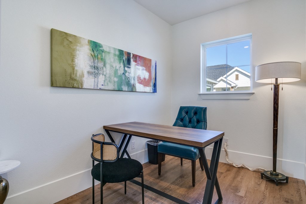 A room with a table and chairs and a painting on the wall.