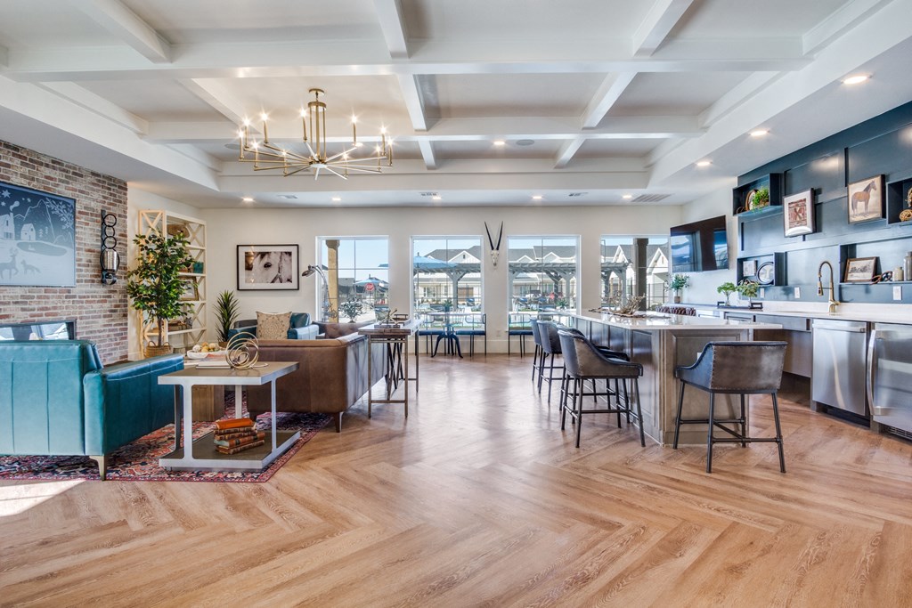 A modern open plan kitchen, dining and living room with wooden floors and a brick wall.