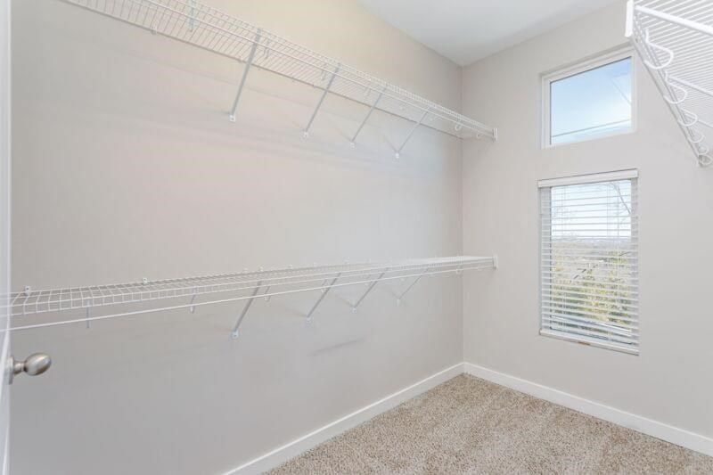 an empty closet with a window and a shelf on the wall