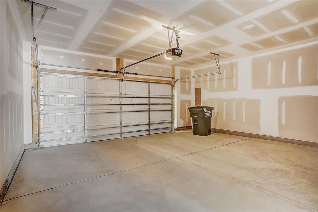 A large empty room with a white ceiling and a white door.