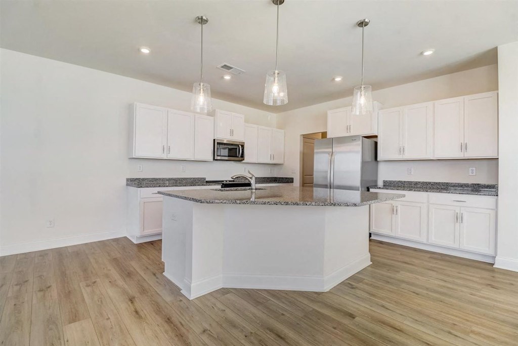 a kitchen with white cabinets and a large island with granite countertops