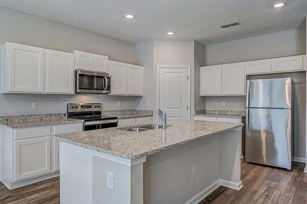 Modern kitchen with white cabinets, granite countertops, stainless steel appliances, and a central island.