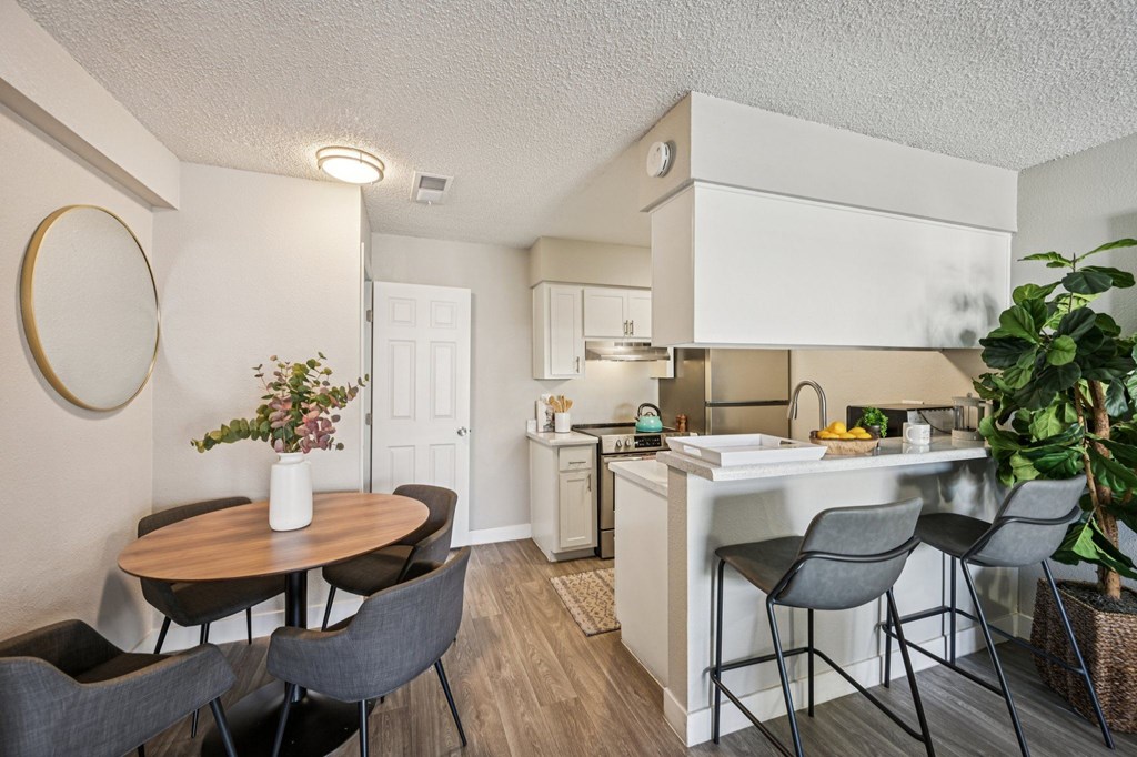 A kitchen with a table and chairs in front of it.