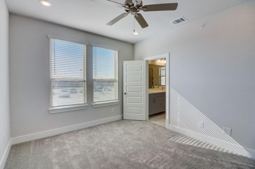 a room with a ceiling fan and a door to a bathroom
