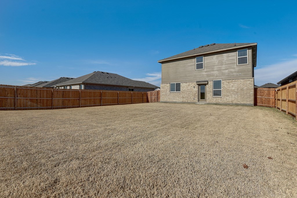 a large yard with a house and a wooden fence