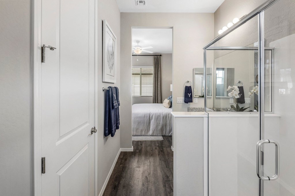 A white bathroom with a mirror and a towel hanging on the door.