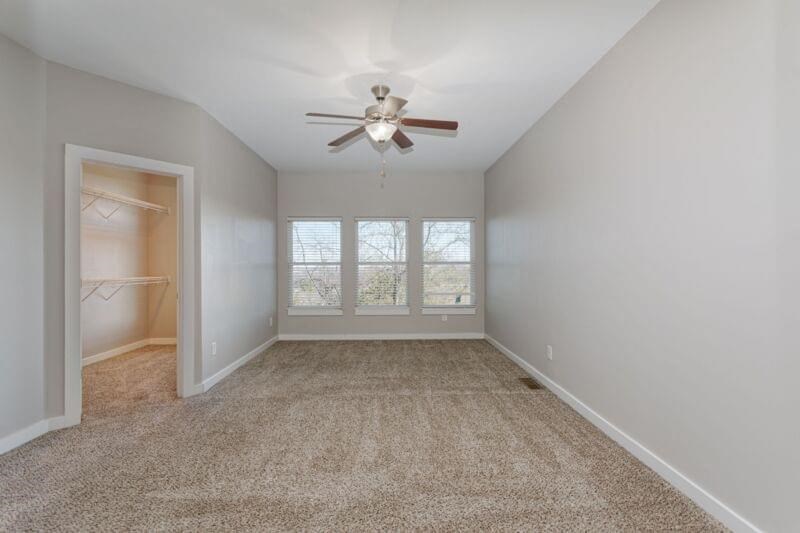 an empty bedroom with a ceiling fan and a closet