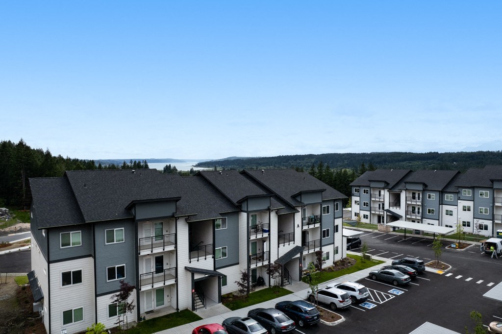an aerial view of a large apartment complex with a lake in the background,