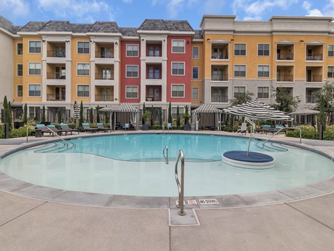 A large swimming pool in front of a multi-story apartment building.
